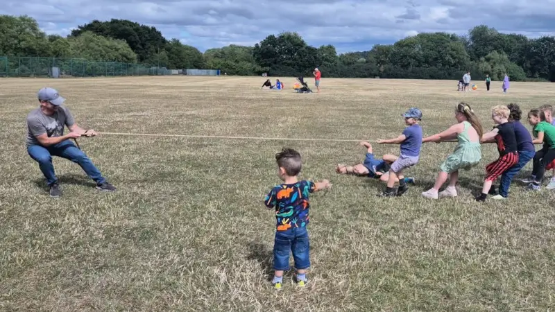 man playing tug of war with children